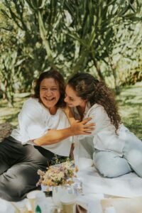 A mother and daughter sharing a joyful moment outdoors surrounded by greenery.